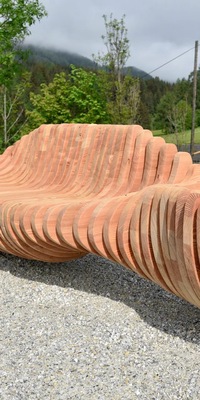 Panchina moderna in legno con design a strati in un parco montano verde